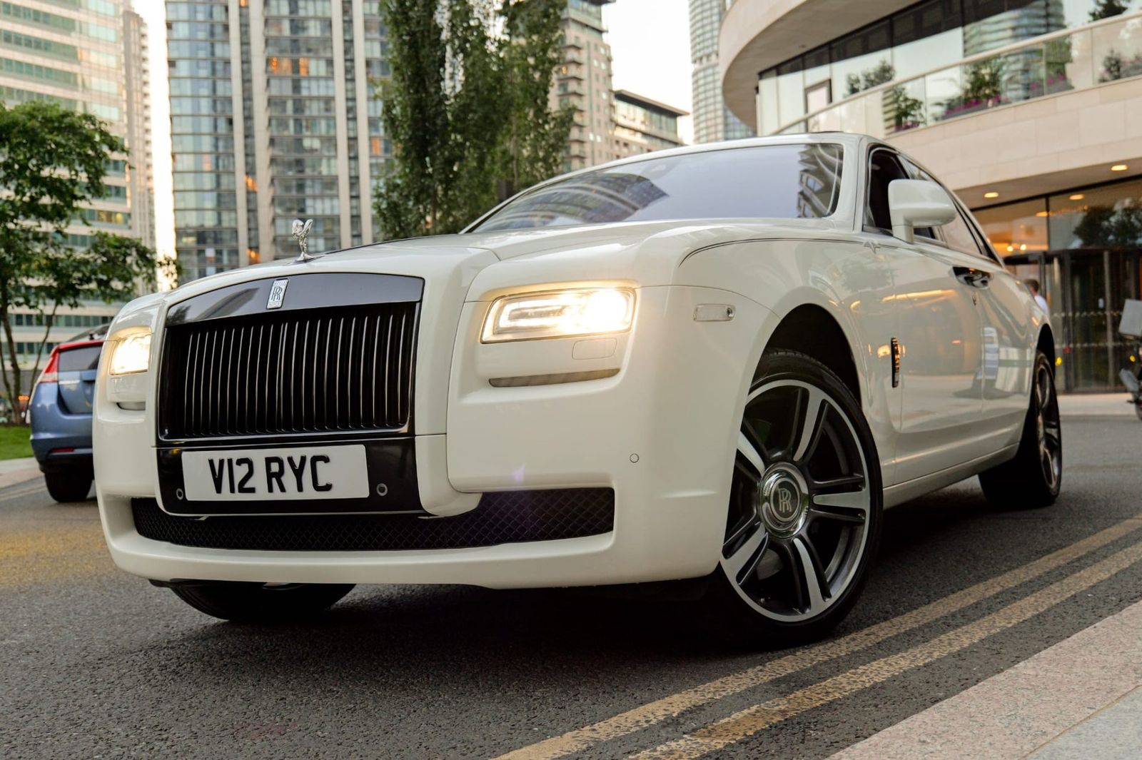 White Rolls-Royce Ghost with Spirit of Ecstasy outside a city skyline